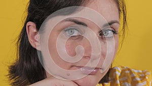 Portrait of a beautiful young woman looking thoughtfully at the camera. Static emotions of a woman on a yellow