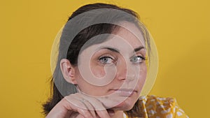 Portrait of a beautiful young woman looking thoughtfully at the camera. Static emotions of a woman on a yellow