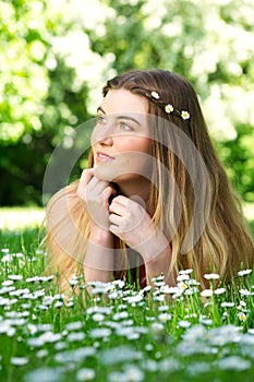 Portrait of a beautiful young woman lying on green grass outdoors