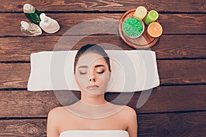 Portrait of beautiful young woman lying in sauna with lotions and candles