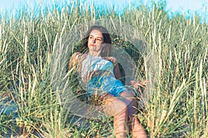 Portrait of a beautiful young woman on meadow watching the sunset enjoying nature summer evening outdoors