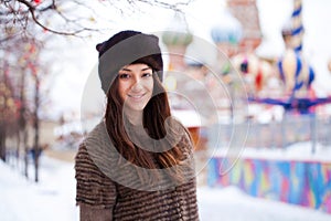 Portrait of a beautiful young woman in a mink hat on a red square