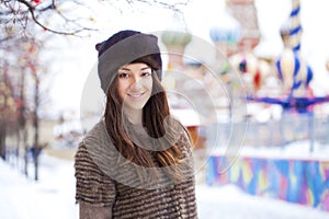 Portrait of a beautiful young woman in a mink hat on a red square