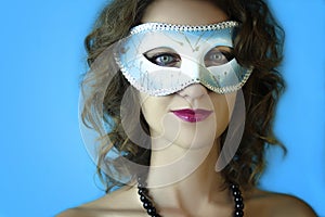 Portrait of beautiful young woman in mysterious blue carnival mask. Fashion and beauty photo
