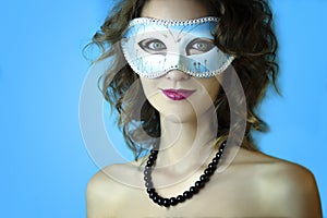 Portrait of beautiful young woman in mysterious blue carnival mask. Fashion and beauty photo