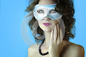 Portrait of beautiful young woman in mysterious blue carnival mask. Fashion and beauty photo