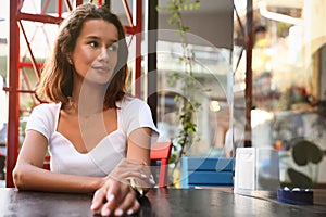 Portrait of beautiful young woman in outdoor cafe. Space for text