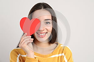 Portrait of beautiful young woman with paper heart