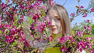 Portrait of beautiful young woman in paradise apple trees blooming park on a sunny day. Springtime. Red apple tree