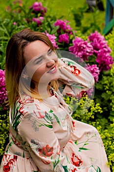 Portrait of a beautiful young woman with peonies flowers outdoors.