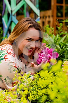 Portrait of a beautiful young woman with peonies flowers outdoors.