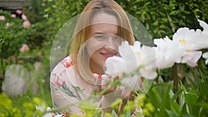 portrait of a beautiful young woman with peonies flowers outdoors.