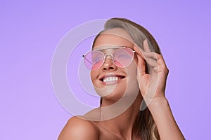 Portrait of beautiful young woman with perfect makeup wearing pink sunglasses.