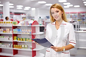 Portrait of beautiful young woman pharmacist at modern drugstore