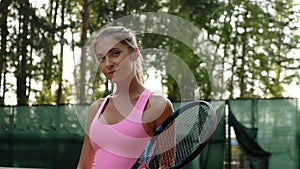 Portrait of beautiful young woman playing tennis on summer court