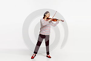 Portrait of beautiful young woman playing violin isolated over white studio background. Tender, lovely sound