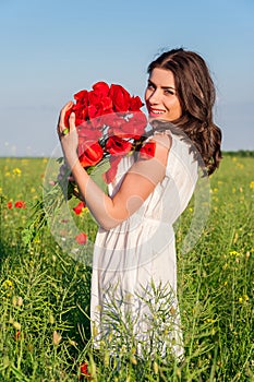 Portrait of beautiful young woman with poppies in the field with a poppies bouquet.