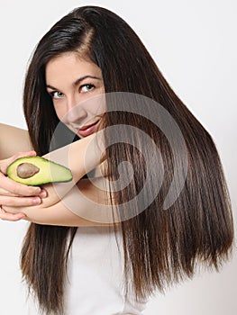 Portrait of a beautiful young woman posing with an avocado over white isolated background