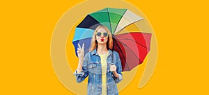 Portrait of beautiful young woman posing with colorful umbrella isolated on yellow background