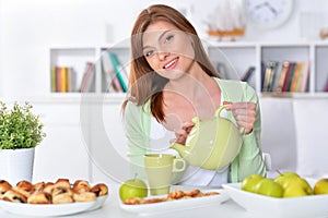 Portrait of beautiful young woman pouring tea in cup