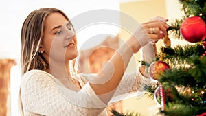 Portrait of beautiful young woman preparing Christmas tree for winter holidays