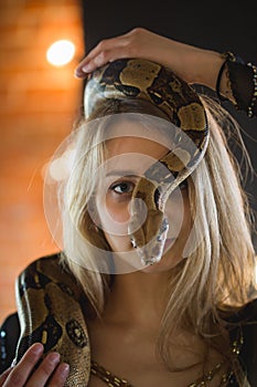 Portrait of beautiful young woman with a python on face