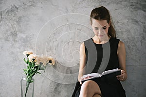 Portrait of a beautiful young woman reading book relaxing in living room. Vintage effect style pictures