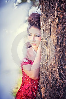 Portrait of beautiful young woman of red dress posing in forest