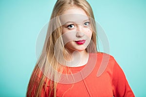 Portrait of beautiful young woman with red lips on blue background. Blonde girl looking at the camera