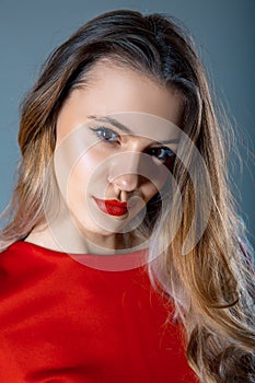 Portrait of beautiful young woman with red lips and red dress on blue gray background