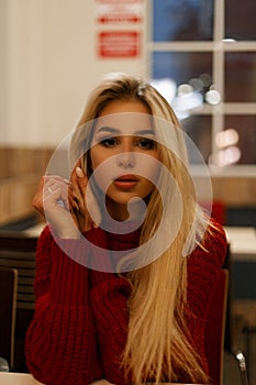 Portrait of a beautiful young woman in a red sweater at a cafe