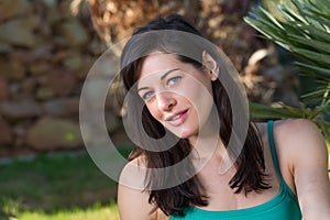 Portrait of beautiful young woman relaxing on grass with palm tr