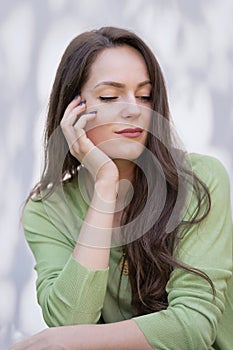 Portrait of an attractive brunette haired woman relaxing at white background outside