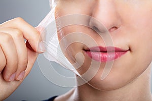 Woman Removing Peeling Mask From Her Face photo