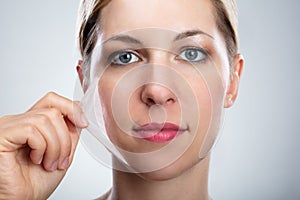 Woman Removing Peeling Mask From Her Face photo