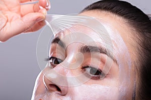 Woman Removing Peeling Mask From Her Face