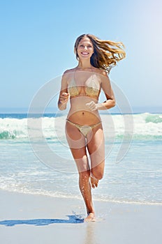 Beautiful and free, just like the sea. Portrait of a beautiful young woman running through the water at the beach.