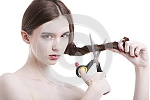 Portrait of beautiful young woman with scissors cutting her hair over white background