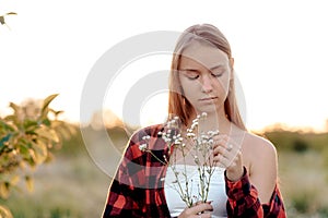 Portrait of a beautiful and young woman in the setting sun divines on daisies