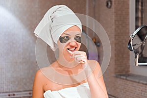 Portrait of a beautiful young woman after shower in patches. female brush teeth in front of her bathroom mirror. healty wellness