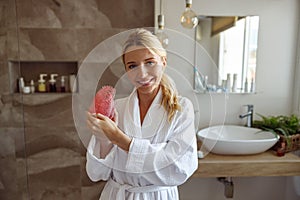 Portrait of beautiful young woman showing anti-cellulite brush massager for firming skin.