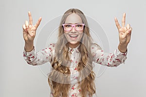 Portrait of beautiful young woman showing peace sign and toothy