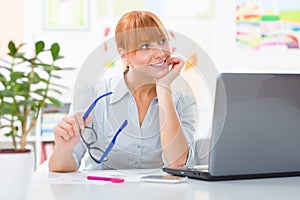 Portrait of beautiful young woman sitting her desk and working at her home