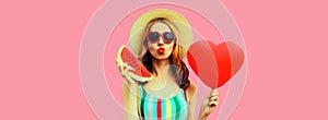 Portrait of beautiful young woman with slice of fresh watermelon and big red heart shaped balloon blowing her lips wearing summer