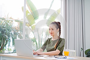 Portrait of a beautiful young woman smiling and looking at laptop screen