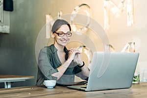 Portrait of a beautiful young woman smiling and looking at laptop screen