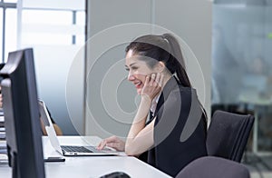 Portrait of a beautiful young woman smiling and looking at laptop screen