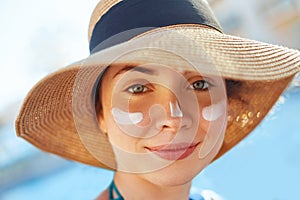 Portrait of a beautiful young woman, smiling, in a swimsuit, smeared face with sun protection cream