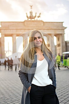 Portrait of beautiful young woman standing in front of Brandenburg Gate in Berlin, Germany.