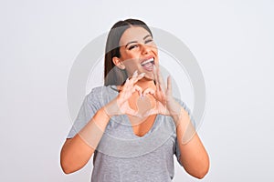 Portrait of beautiful young woman standing over isolated white background smiling in love doing heart symbol shape with hands